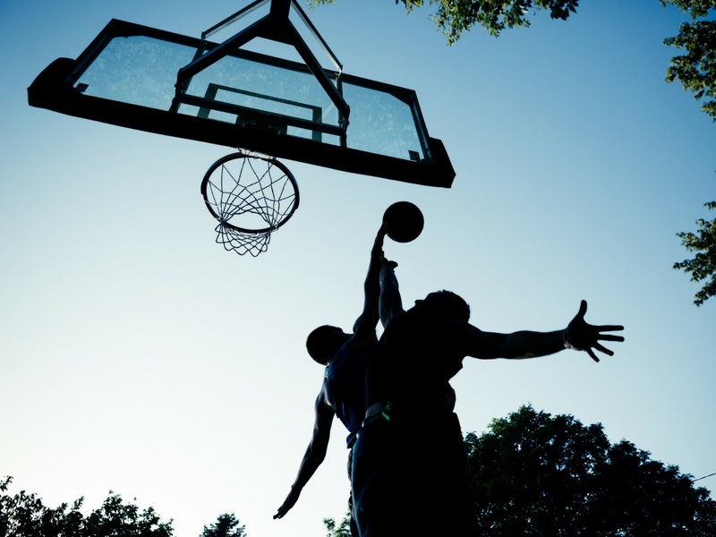 Silhouette of basketball players: one going for a layup while the other successfully blocks it